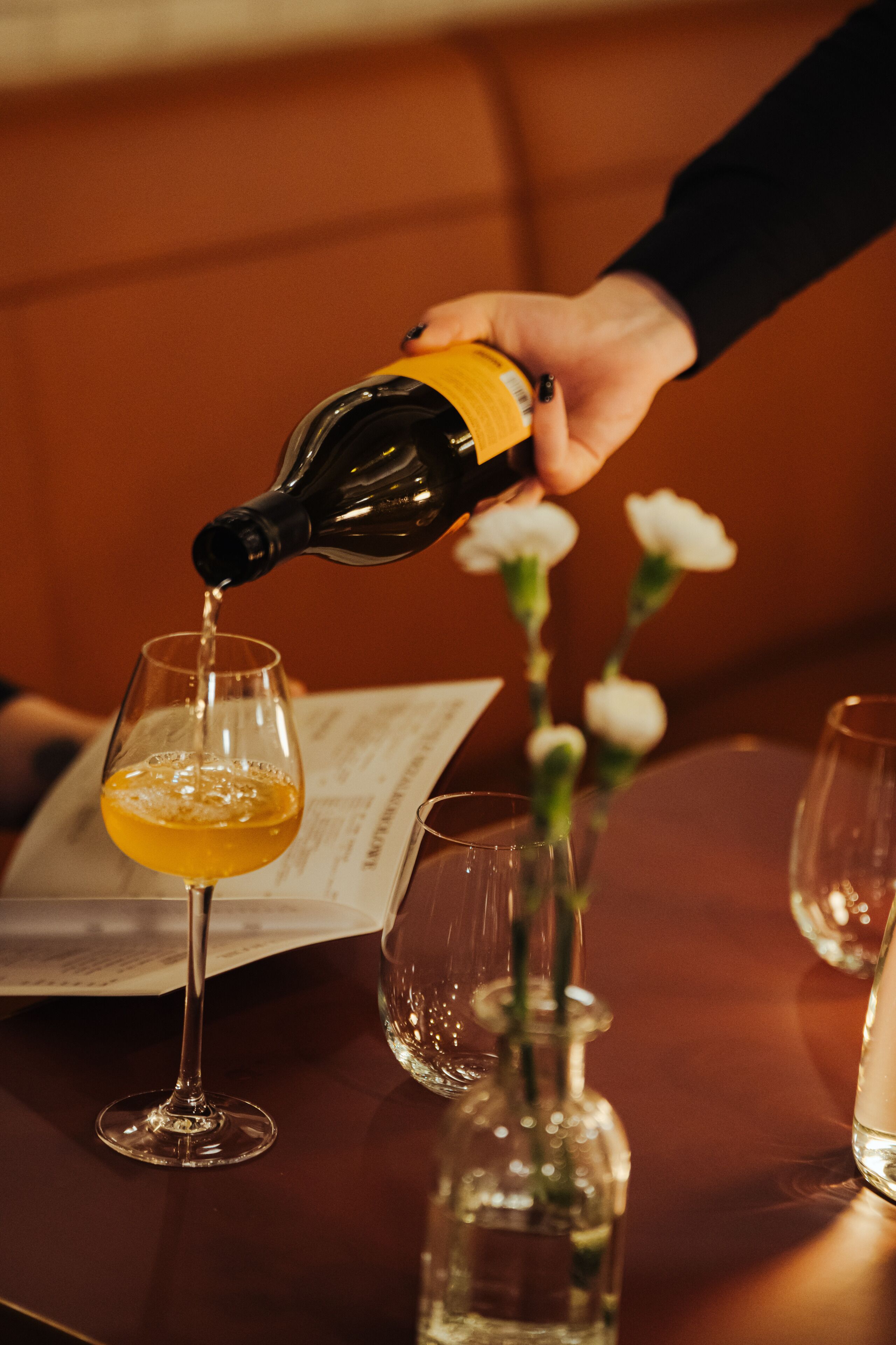 Een hand giet een drankje in een glas.