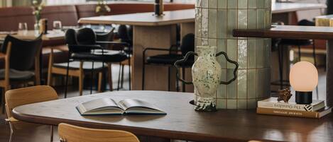 A modern dining area with a round table, wooden chairs, a decorative vase, and a book.