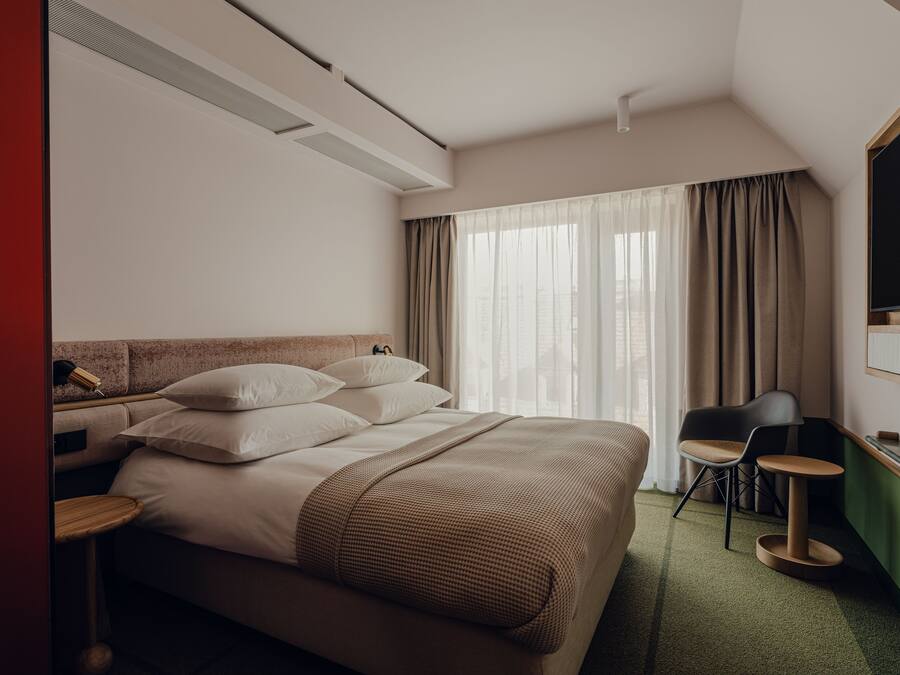 A hotel room with a large bed, a desk, a chair, and a TV.