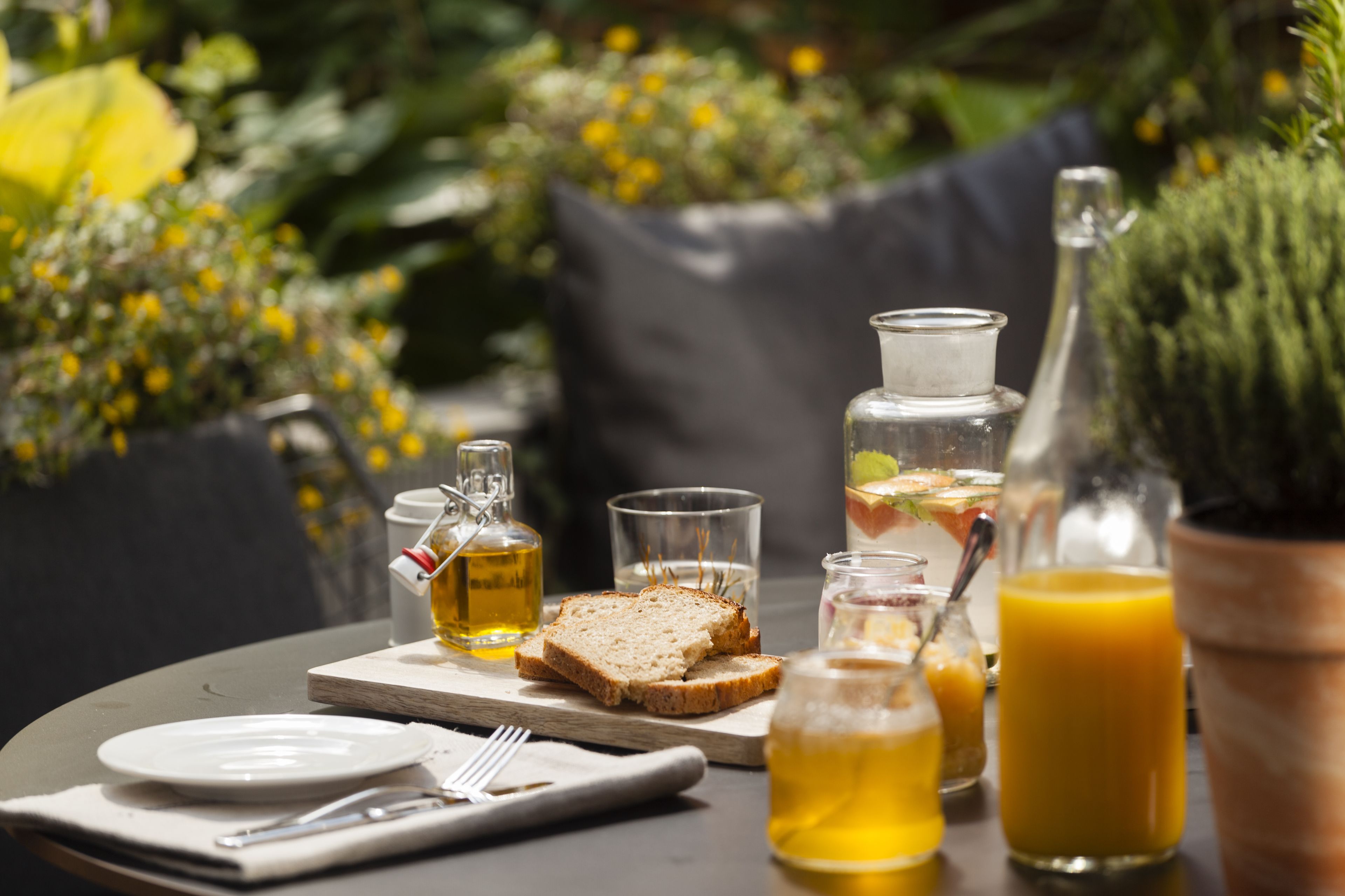 Ein Tisch, reichhaltig gedeckt mit Frühstücksleckereien, darunter Toast, ein Glas Saft und eine Ölflasche.