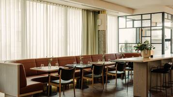Un comedor moderno con barra de madera, asientos acolchados y ventanas amplias.