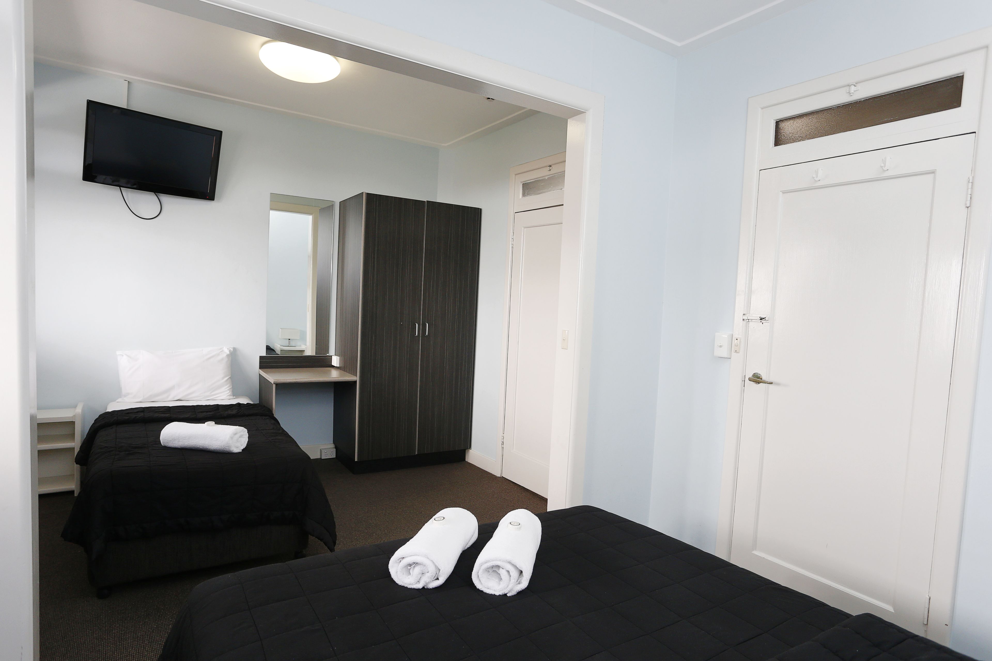 Habitación de hotel con dos camas, un televisor, un armario y una puerta.