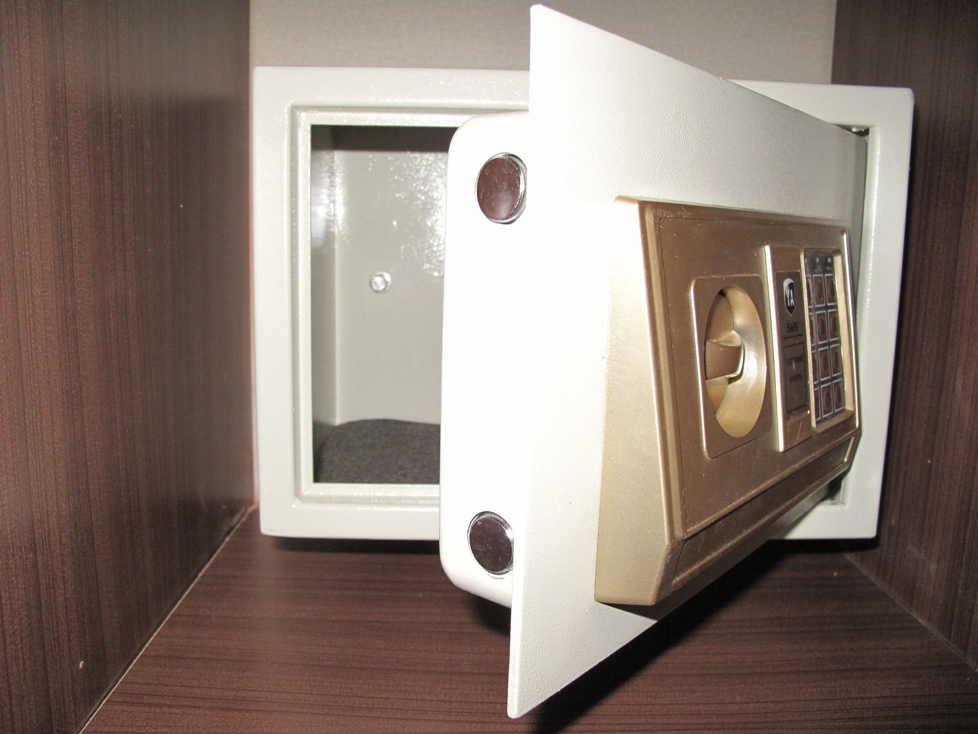 A white safe with a combination dial and a keyhole, placed on a wooden surface.