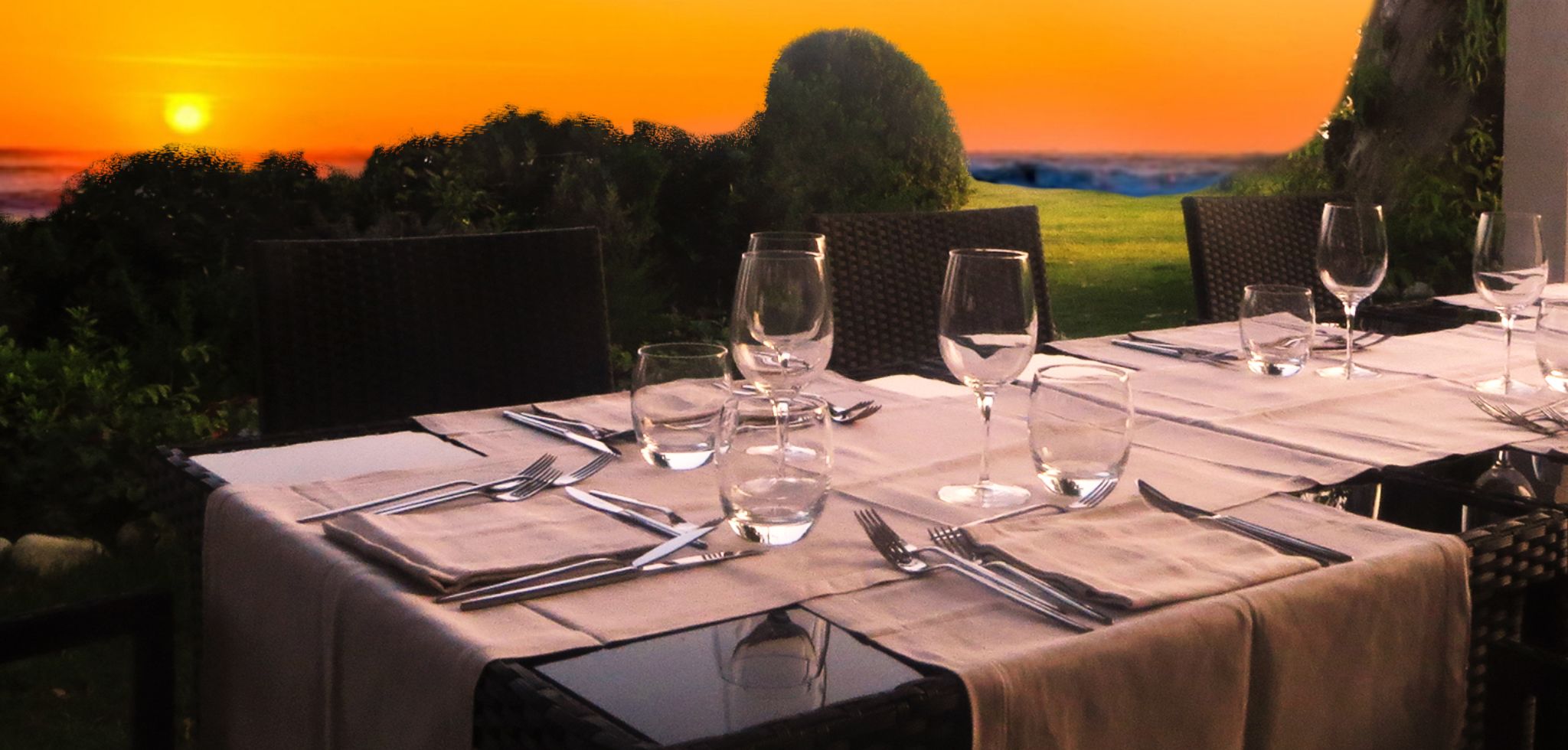 Ein Tisch, gedeckt für ein Abendessen, mit Blick auf den Sonnenuntergang.