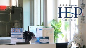 A reception desk with a sign for Hotel Eden Park, a computer, a plant, and some informational brochures. - Hotel Eden Park Cilento (Ispani)