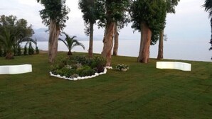 A landscaped garden with a central grassy area, surrounded by white planters and trees. - Hotel Eden Park Cilento (Ispani)