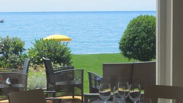 An outdoor dining area with a table set for four, overlooking a body of water.
