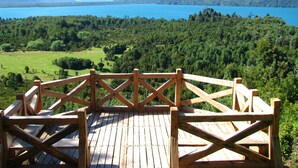 Una terraza de madera con vistas a un lago y montañas.