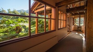 Un pasillo con grandes ventanales que ofrecen vistas de exuberante vegetación y montañas.
