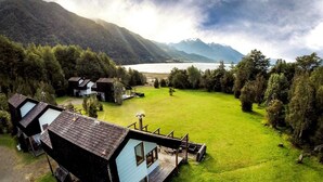 Un albergue de montaña con varias cabañas, un campo cubierto de hierba y un lago.