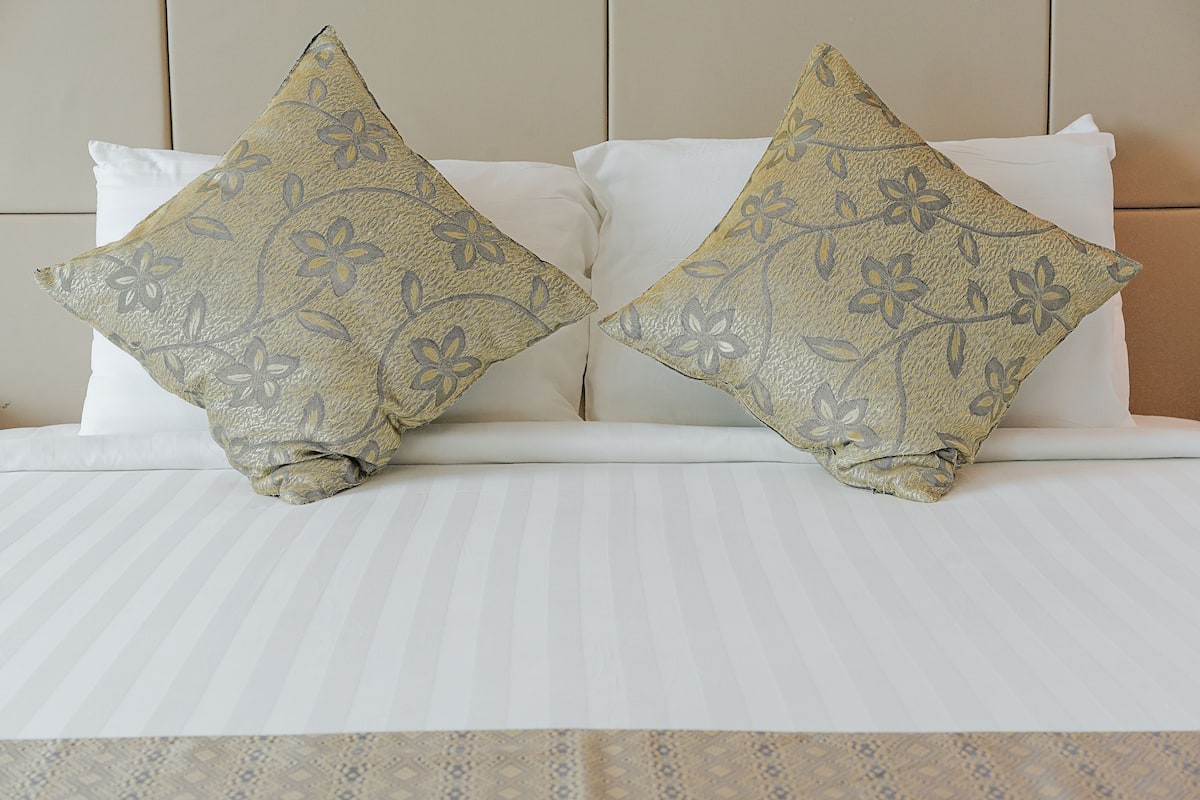 Cama com duas almofadas decorativas e edredom estampado.