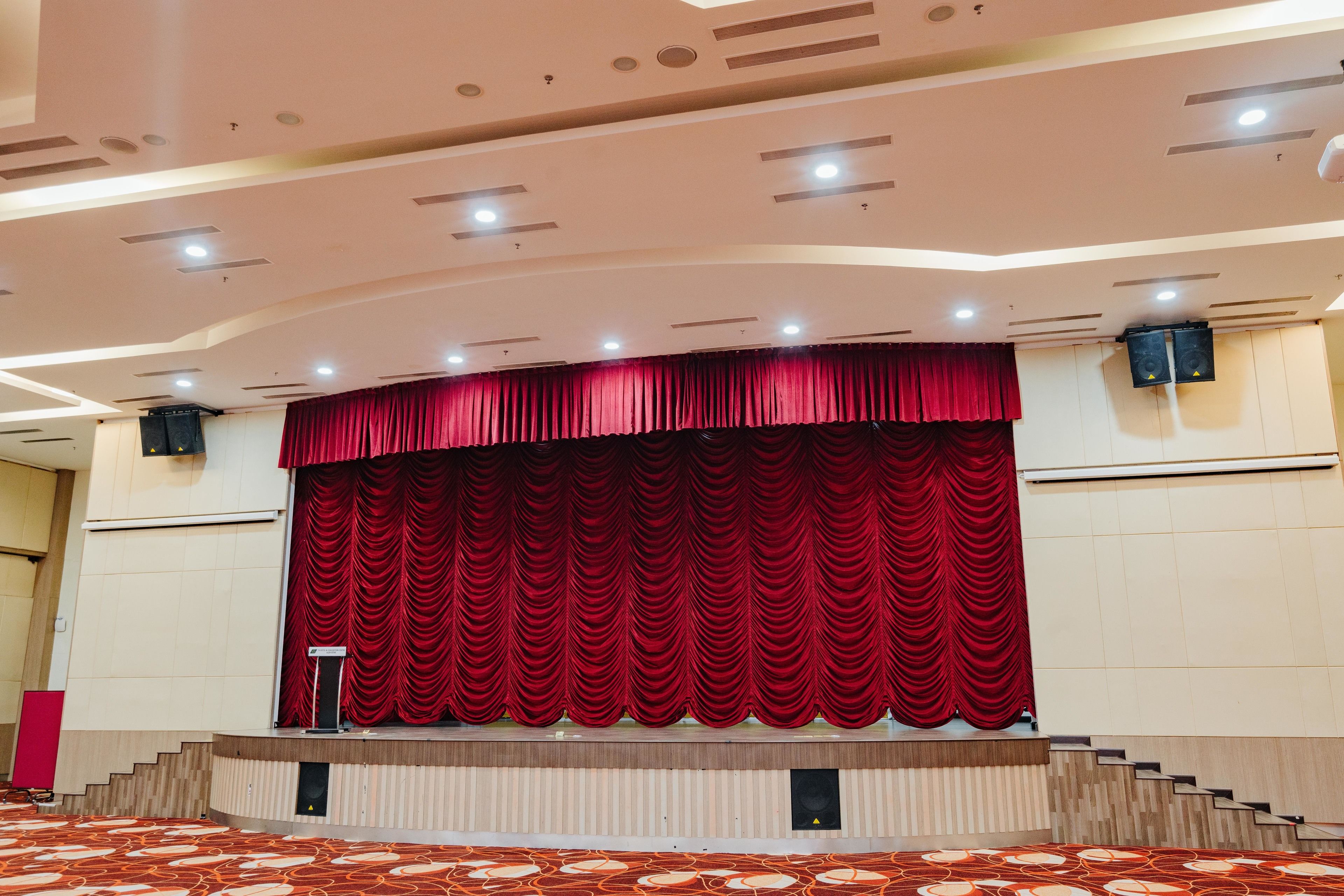 A stage with a red curtain, a podium, and a speaker system.