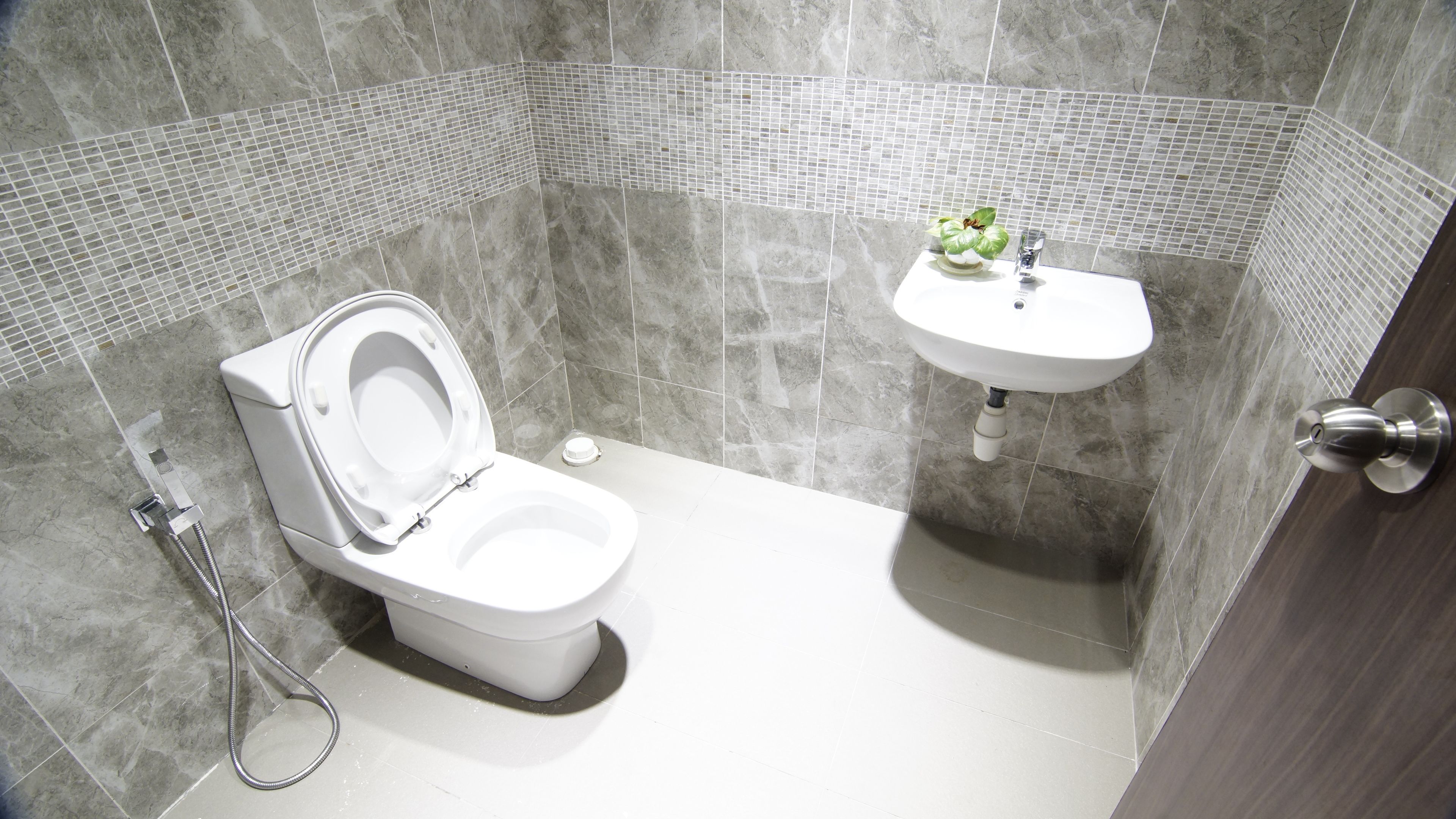 Et badeværelse med toilet, håndvask og brusebad.