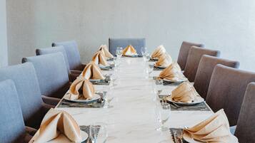 A long dining table with neatly folded napkins, silverware, and clear glasses set for a meal.