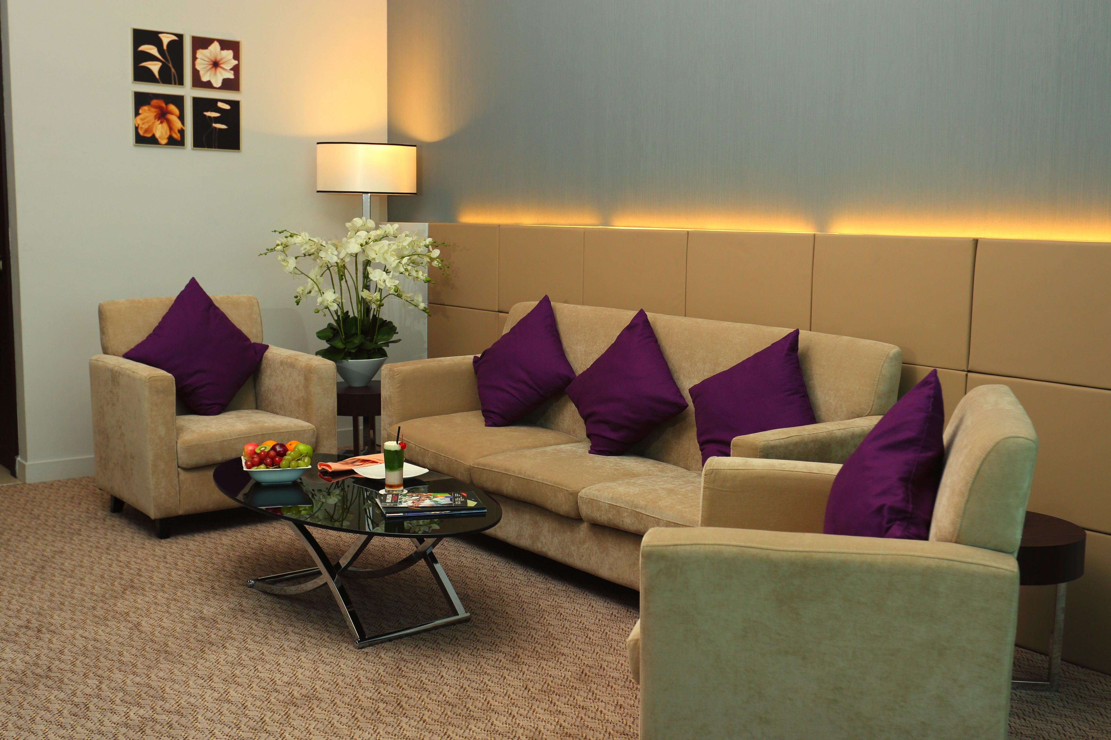 A living room with a beige sofa, two armchairs, a coffee table, and a lamp.