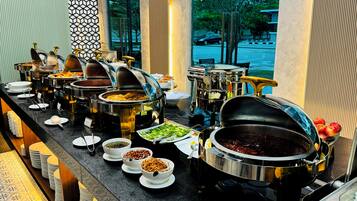 A buffet with various food items and utensils.