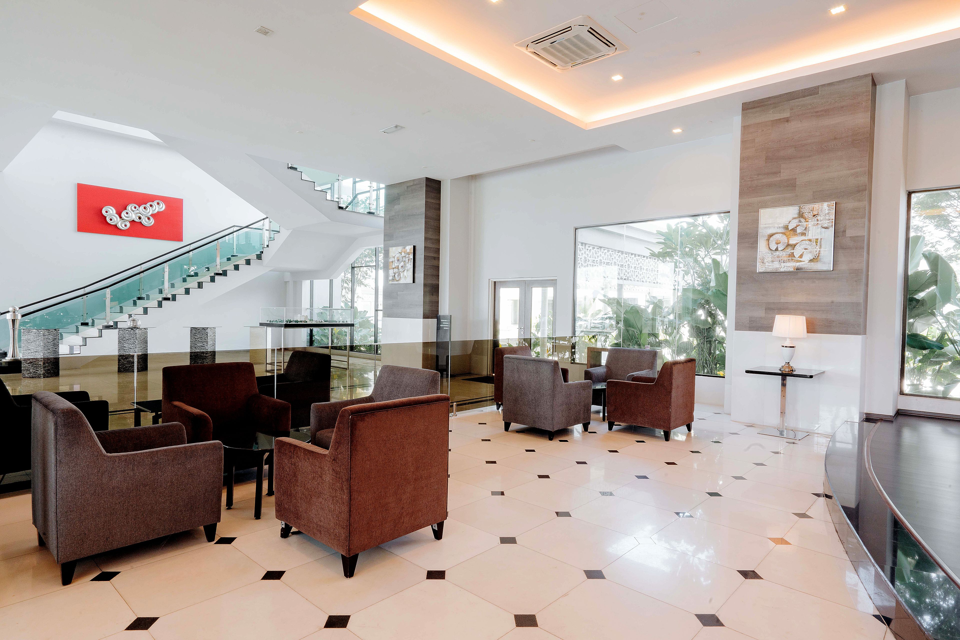 A spacious lobby with a staircase, modern furniture, and large windows.