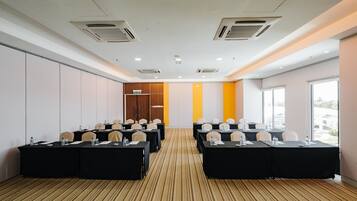 Une salle de conférence dotée de plusieurs tables, de chaises et d’un sol recouvert de moquette.