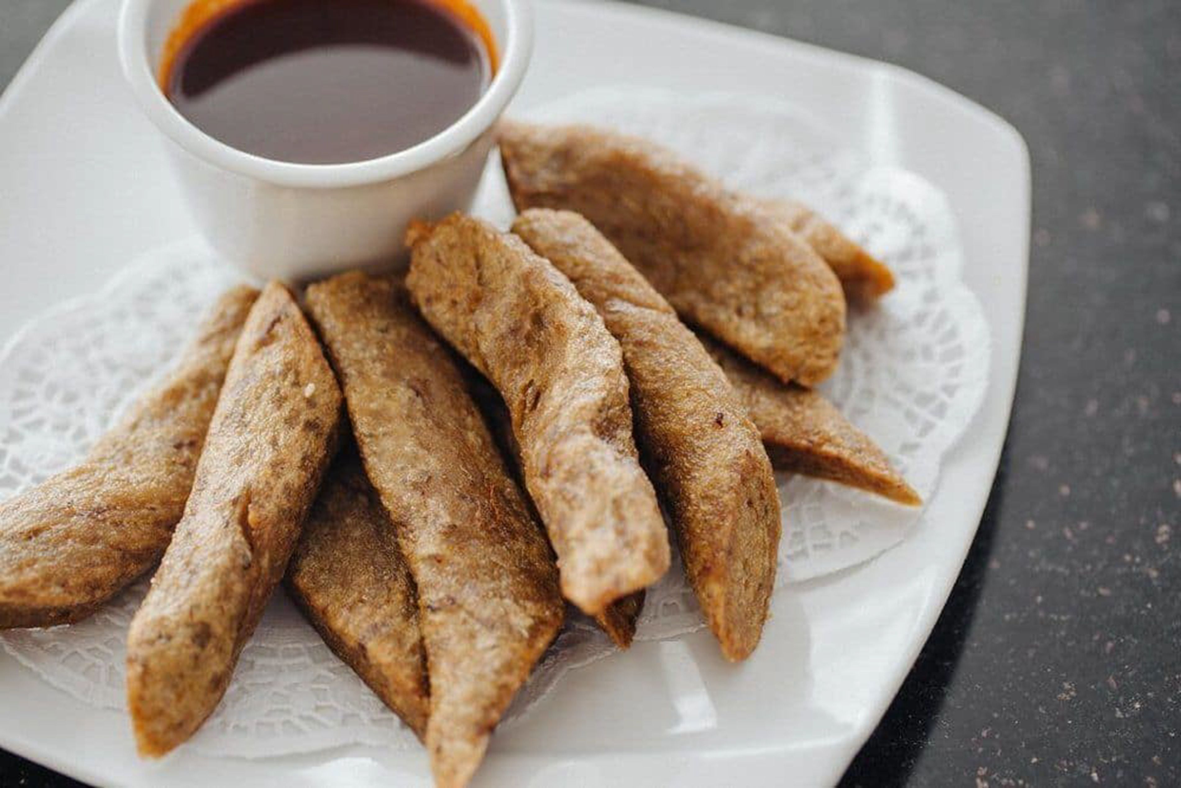 A plate of fried fish with a dipping sauce.