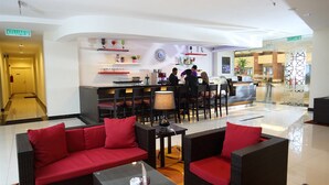 A hotel lobby with a reception desk, seating area with red cushions, and a clock on the wall. - Raia Hotel & Convention Centre Terengganu (Kuala Terengganu)