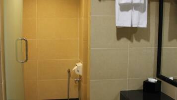Une salle de bain avec une douche, une barre d’appui, un porte-serviettes avec une serviette blanche et un lavabo noir.