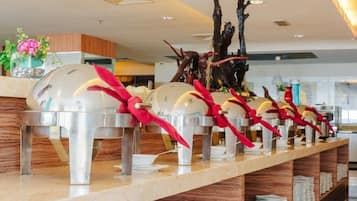 Un buffet composé de plusieurs tables de service, chacune agrémentée d’un saladier blanc et d’une serviette rouge attachée à son anse.