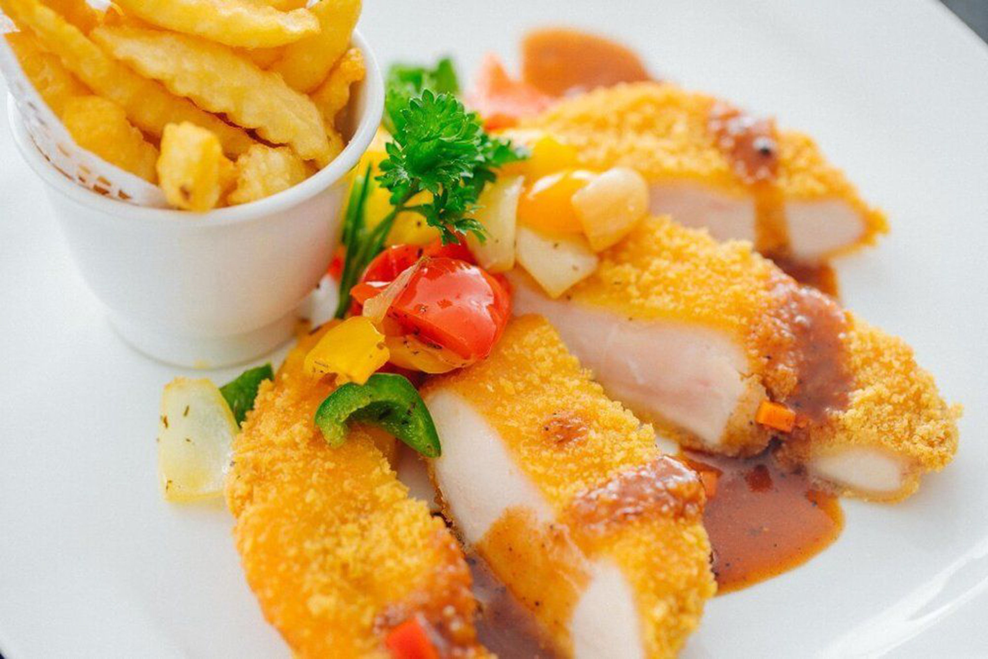 Une assiette contenant des filets de poisson panés, une portion de frites et une garniture de légumes.