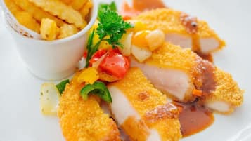 Un plato con filetes de pescado empanizado, papas fritas y una guarnición de verduras.