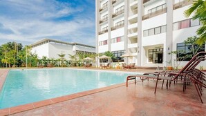 A hotel with a swimming pool, outdoor seating, and a multi-story building with balconies. - Raia Hotel & Convention Centre Terengganu (Kuala Terengganu)