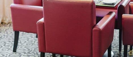 Een eetgedeelte met een tafel gedekt voor vier personen, omringd door rode fauteuils.