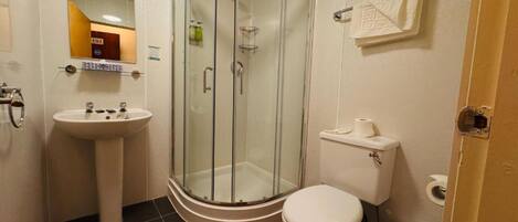 Un baño con ducha de vidrio, lavamanos e inodoro.