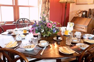 Una mesa de comedor dispuesta con platos, cubiertos y un centro de mesa floral.