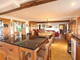 Una cocina amplia con armarios de madera, una isla central y un comedor con sillas.