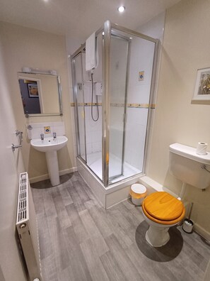 A modern bathroom with a glass-enclosed shower, a pedestal sink, and a toilet with a wooden seat. - Northover Manor Hotel (Yeovil)