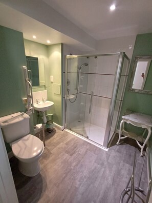 Un baño moderno con ducha de mampara de vidrio, inodoro y lavamanos.