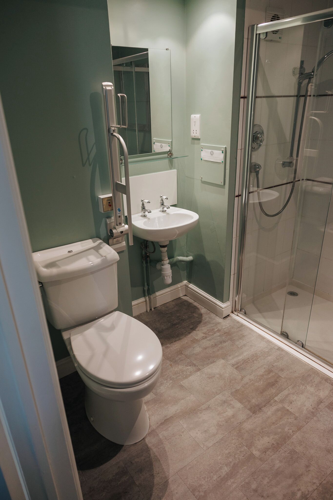 Un baño con inodoro, lavamanos y ducha con mampara de vidrio.