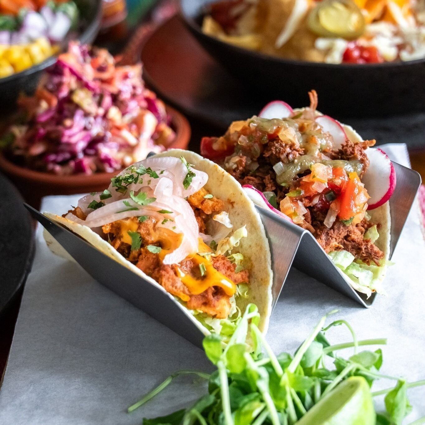 Deux tacos garnis de divers ingrédients et une salade en accompagnement.