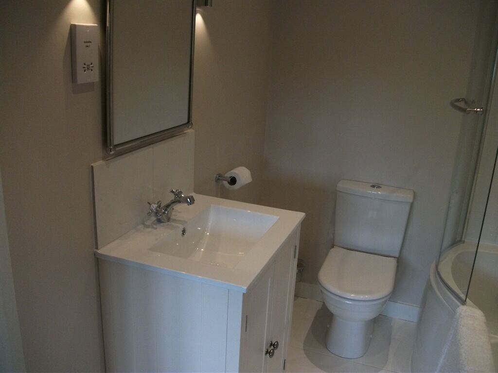 A bathroom with a white sink, a toilet, and a glass shower enclosure.