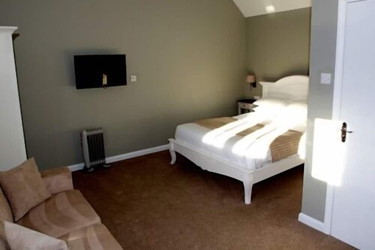 A bedroom with a bed, a nightstand, a wall-mounted TV, and a radiator.