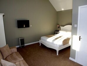 A bedroom with a bed, a nightstand, a wall-mounted TV, and a radiator.
