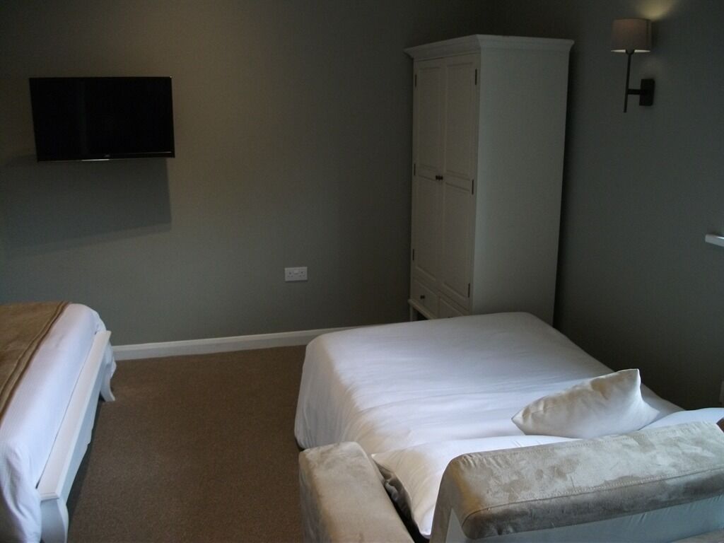 Camera da letto con due letti, un armadio, una TV a schermo piatto e un punto luce a parete.