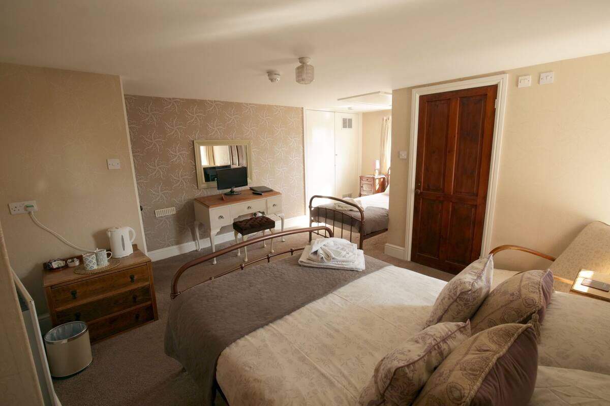 A hotel room with a bed, bedside table, dresser, and a mirror.