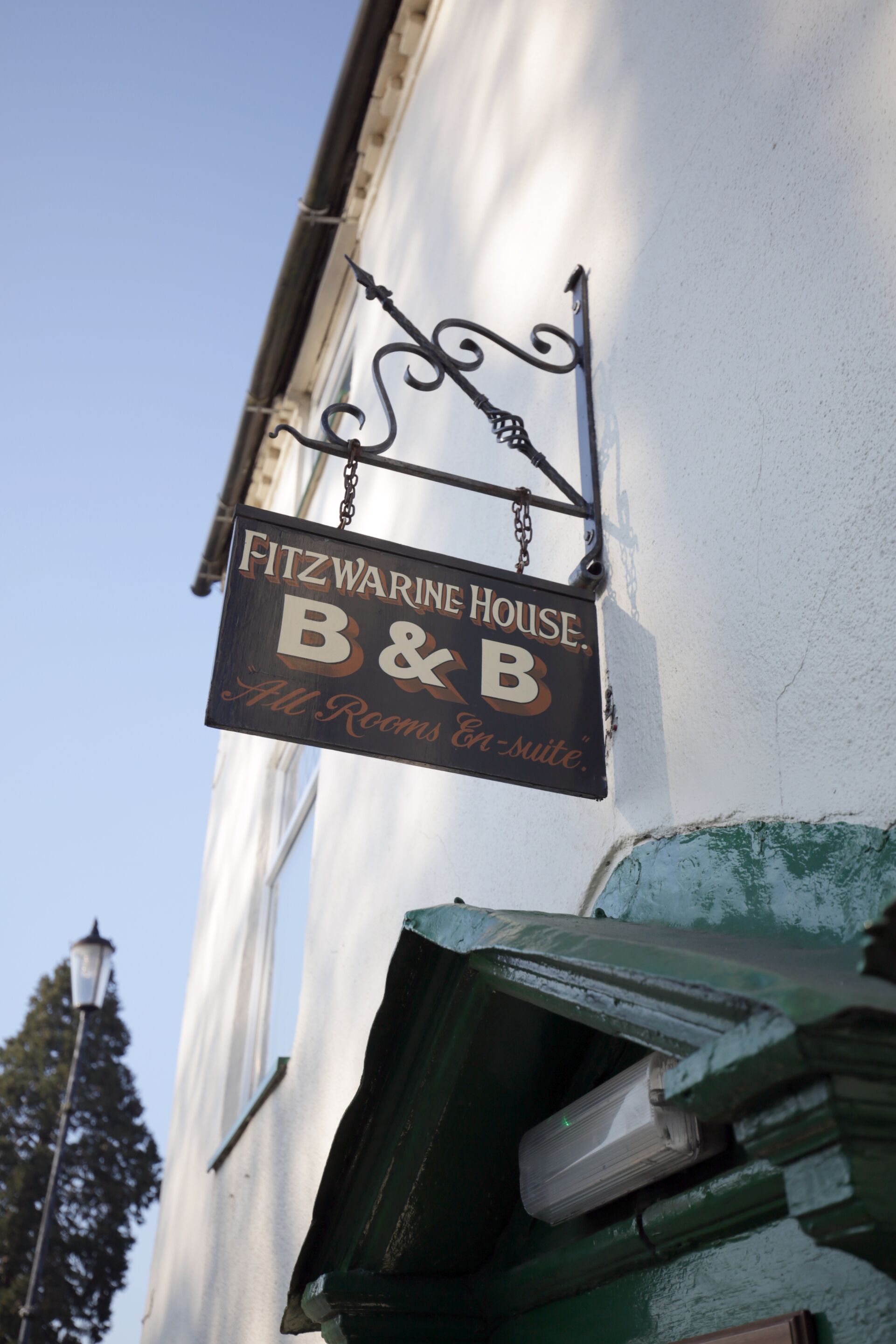 A sign for Fitzwarine House B&B, indicating it offers all rooms and en-suite bathrooms.