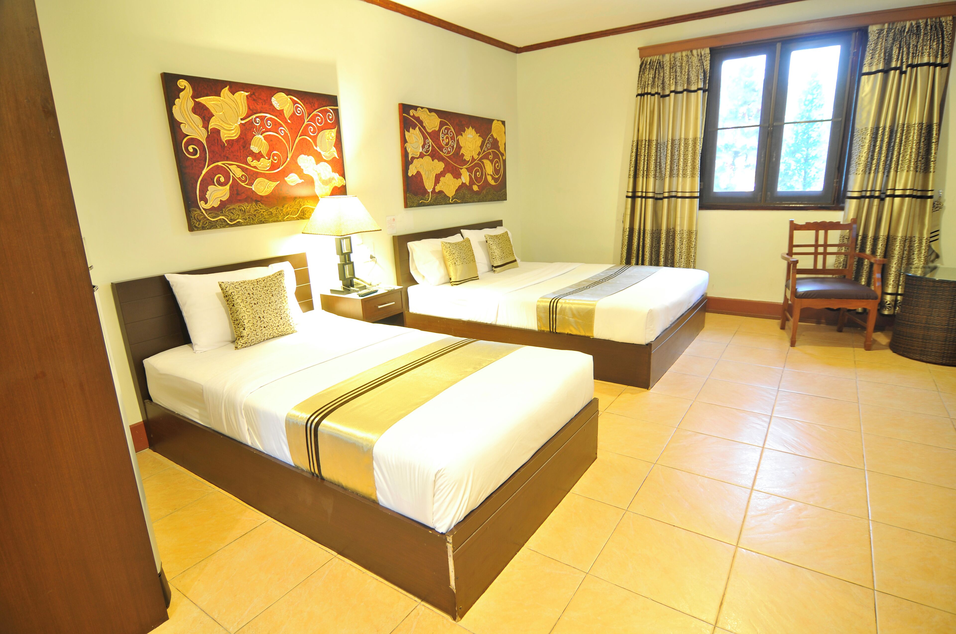 A hotel room with two beds, a nightstand, a chair, and artwork on the walls.