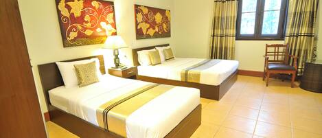 A hotel room with two beds, a nightstand, a chair, and artwork on the walls.
