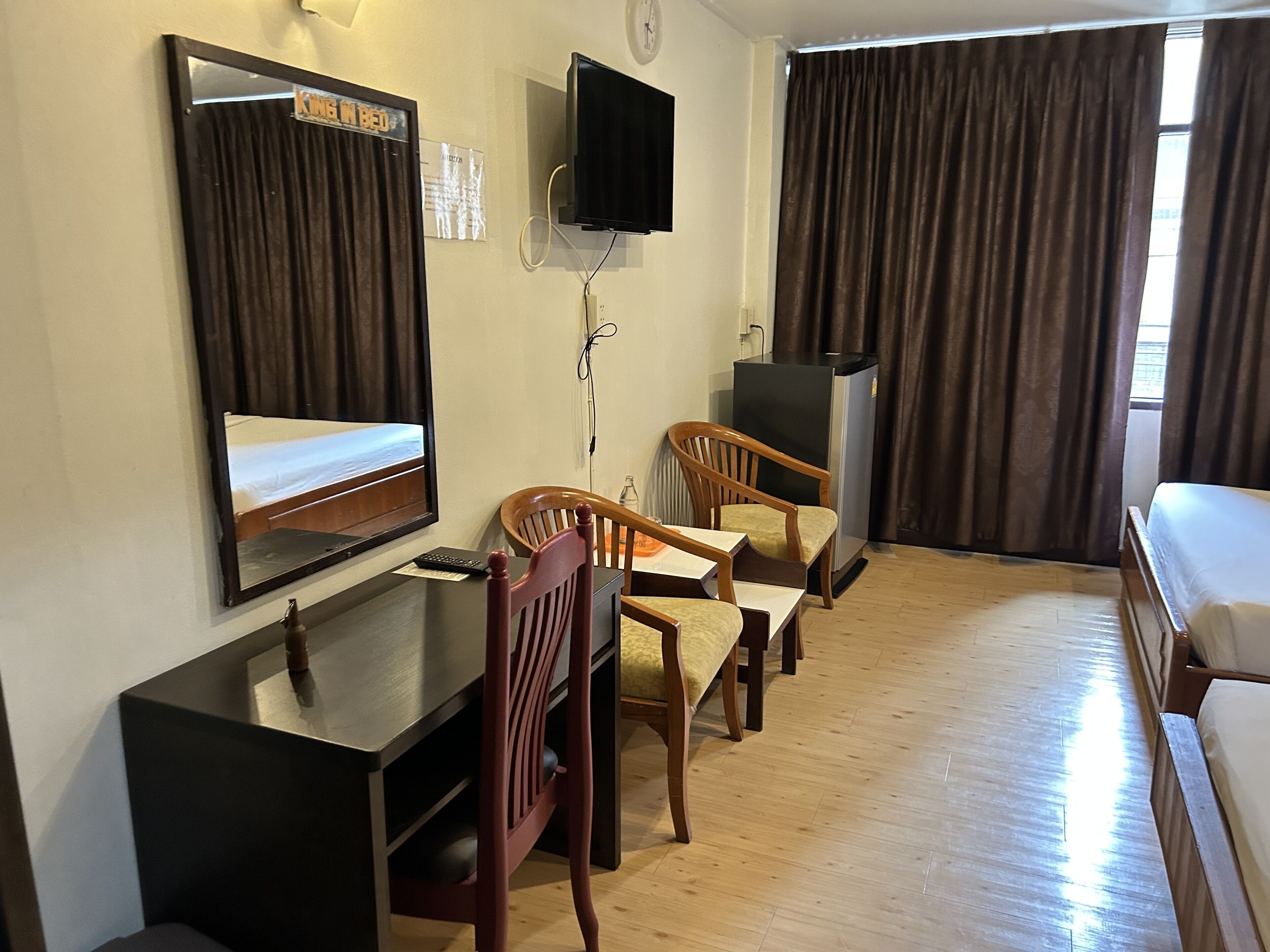 Een hotelkamer met een bed, een bureau met stoel, een televisie en een raam met gordijnen.