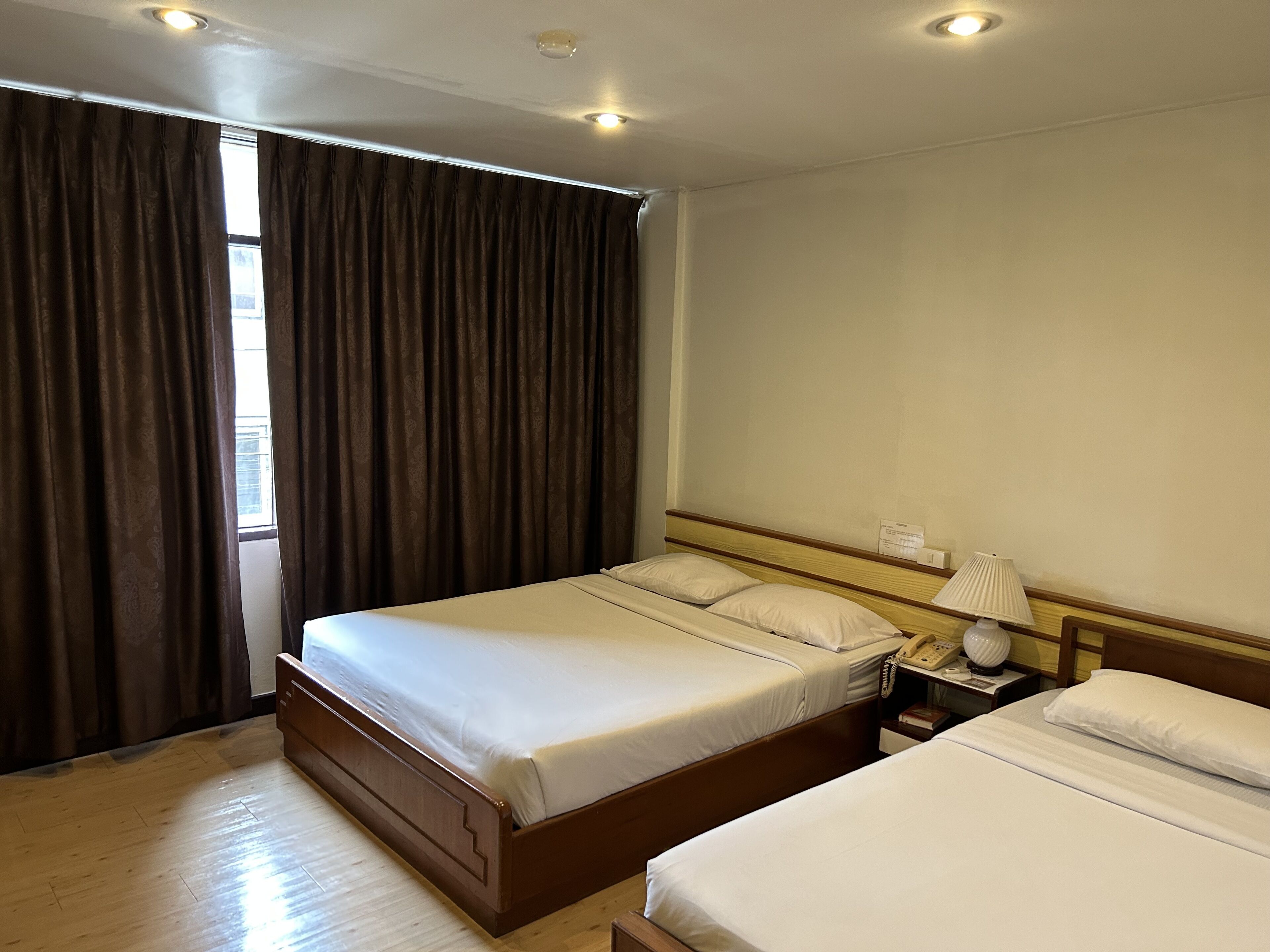 A hotel room with a large bed, bedside tables, and a window with curtains.
