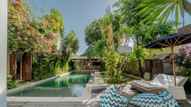 A wooden deck with a pool, surrounded by lush greenery and a gazebo. - Villa Saffira (Seminyak)