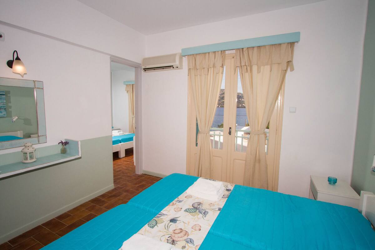 A bedroom with a bed, a nightstand, a mirror, and a bathroom visible through an open door.