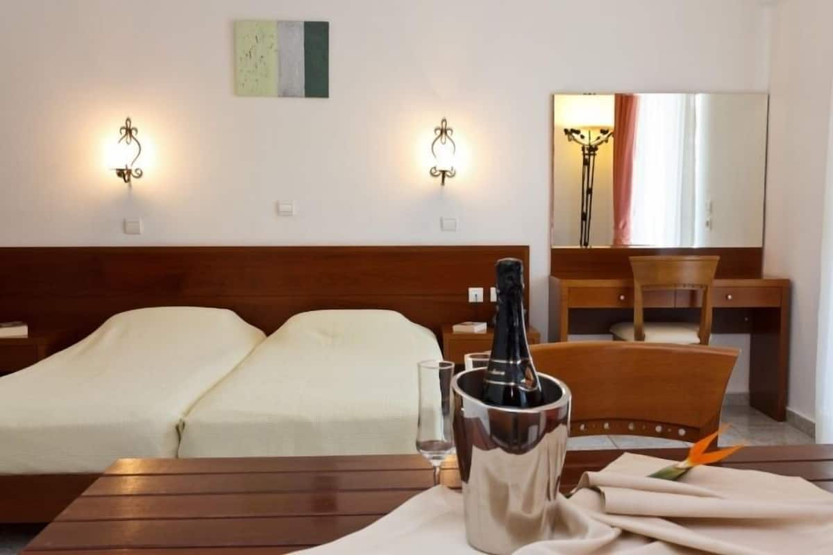 Ein Hotelzimmer mit einem Bett, einem Schreibtisch und einem Tisch mit einer Champagnerflasche.
